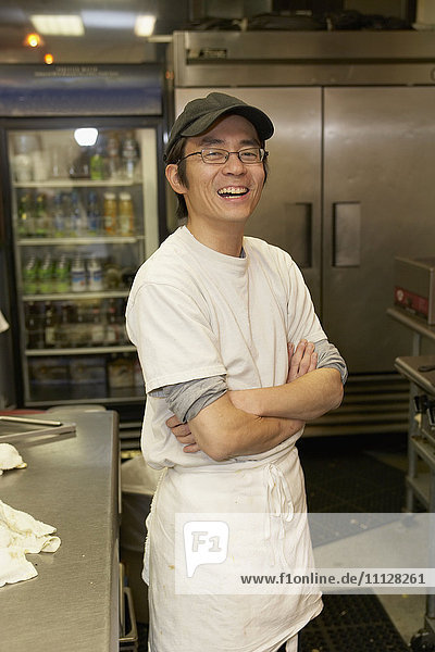 Japanischer Chefkoch lächelt mit verschränkten Armen