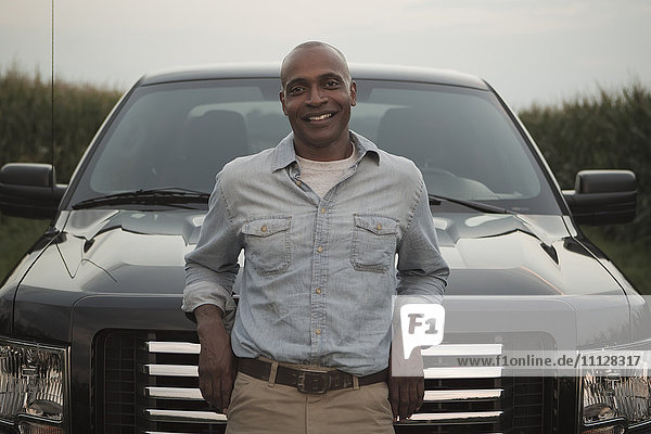 African American man leaning on hood of car