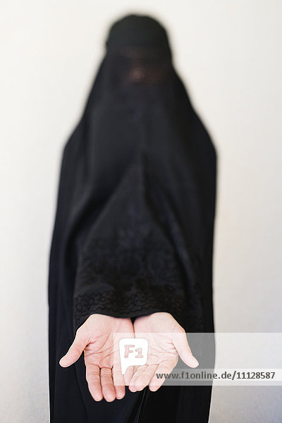 Frau aus dem Nahen Osten in Burka mit ausgestreckten Händen