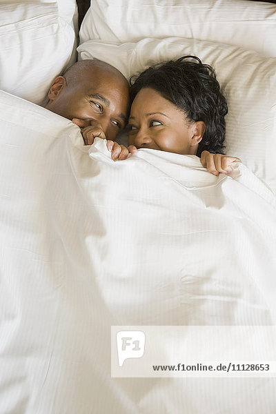 African couple in bed under blanket