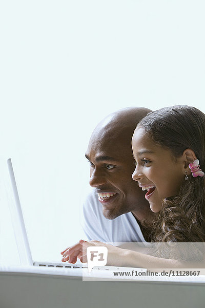 Gemischtrassiger Vater und Tochter benutzen Laptop