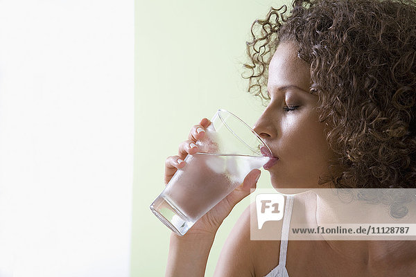 Gemischtrassige Frau trinkt ein Glas Wasser