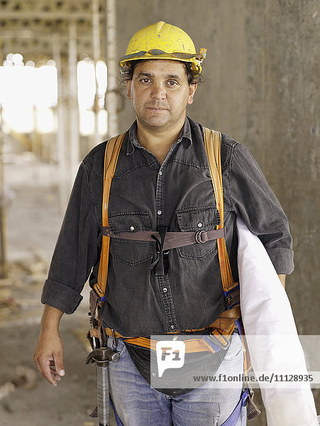 Hispanic worker holding blueprints on construction site
