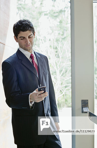 Mixed race businessman looking at cell phone