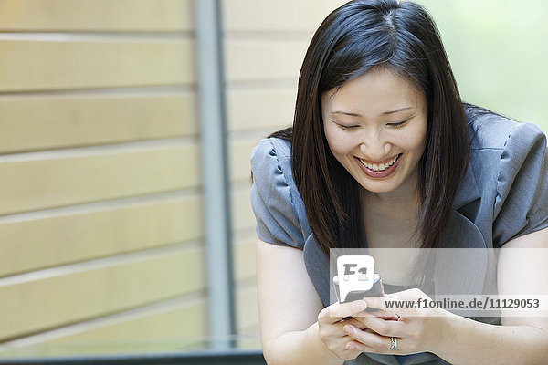 Asiatische Geschäftsfrau schaut auf ihr Handy