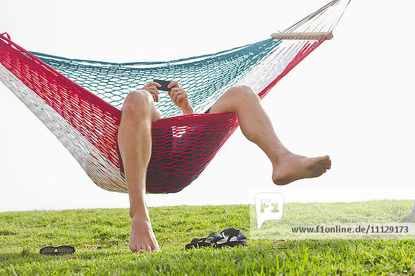 Caucasian man relaxing in hammock with cell phone