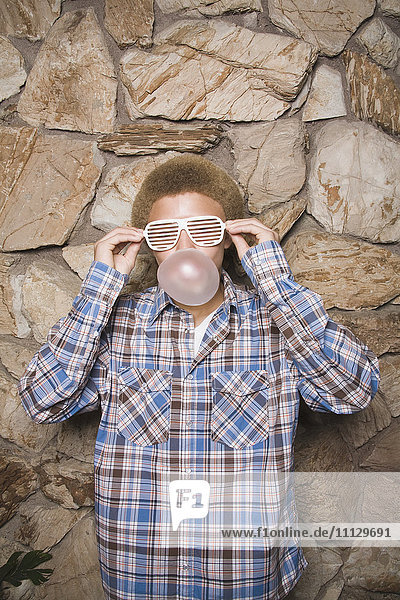Mixed race boy in sunglasses chewing bubble gum