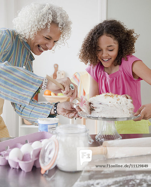 Großmutter und Enkelin glasieren Kuchen