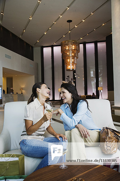 Hispanische Frauen trinken Weißwein in der Hotellobby