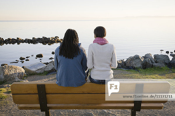 Black couple sitting on bench near shore