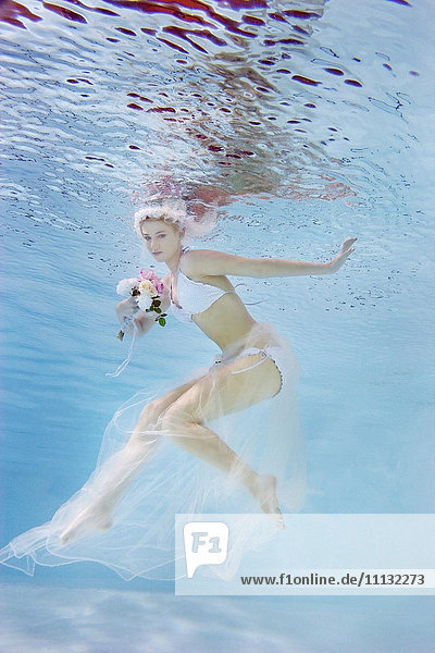 Kaukasische Braut im Bikini schwimmt unter Wasser