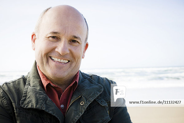 Lächelnder kaukasischer Mann am Strand stehend