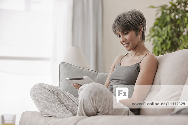 Mixed race woman on sofa using digital tablet