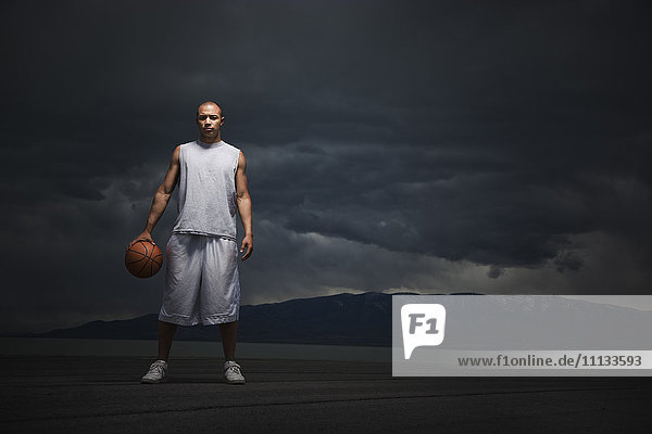Gemischtrassiger Basketballspieler mit Gewitterwolken in der Ferne