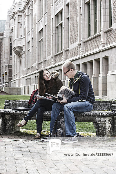 Studenten sitzen zusammen auf einer Bank