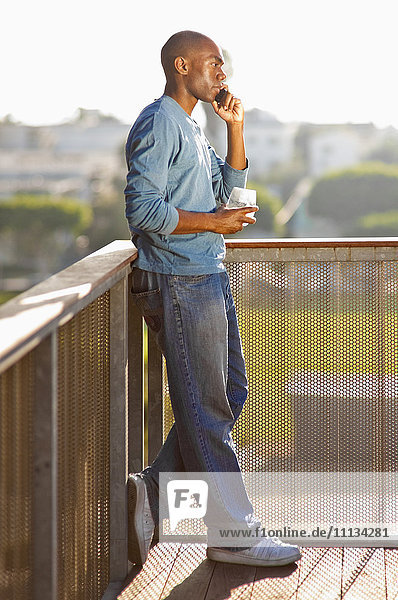 Black man talking on cell phone on balcony