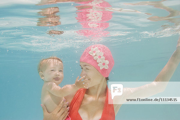 Kaukasische Mutter hält Baby unter Wasser