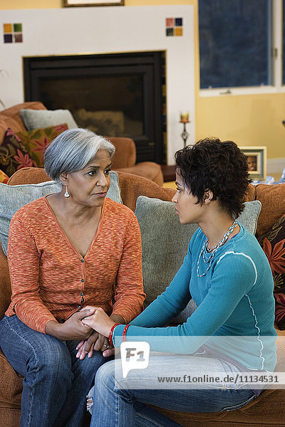 African American mother talking with daughter in living room