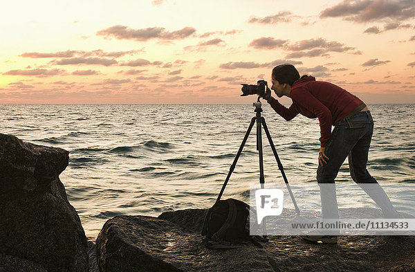 Gemischtrassige Frau benutzt Kamera in Meeresnähe