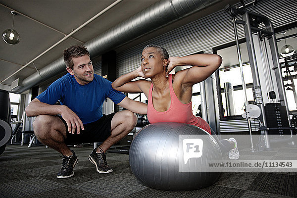 Personal Trainer hilft Frau im Fitnessstudio