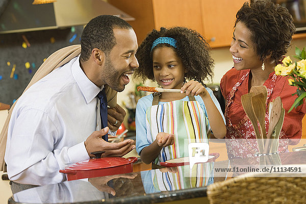 African American girl giving father a taste of sauce