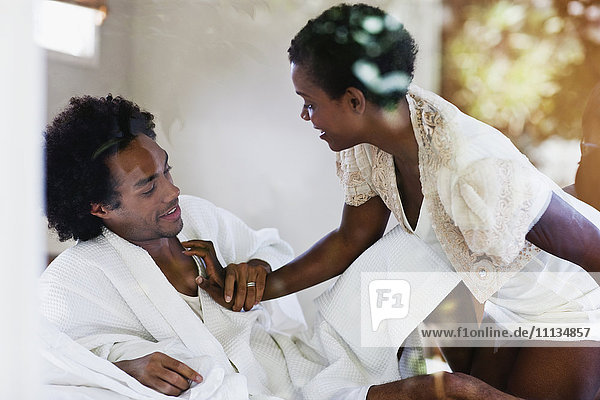 Afroamerikanische Frau kniend auf dem Bett mit Ehemann