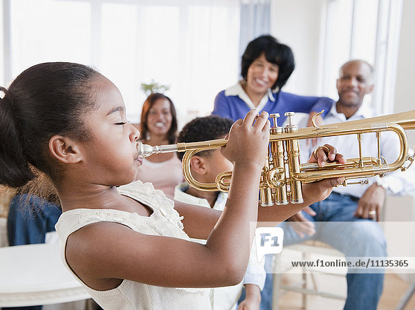 African American family watching daughter play trumpet