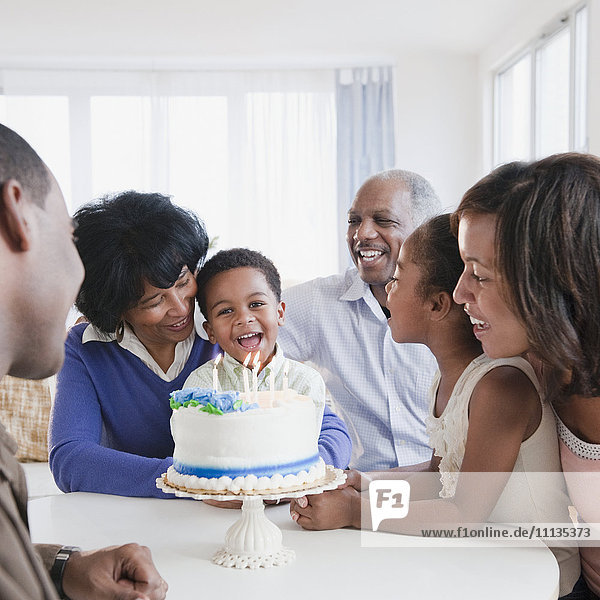 African American family watching grandson blow out birthday candles