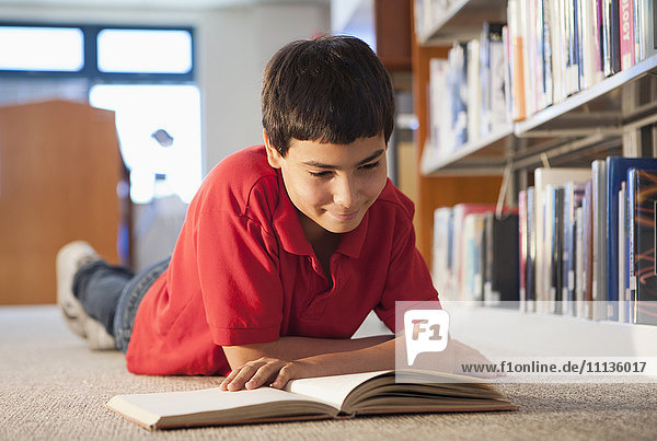 Hispanic boy reading book in library