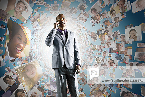 African American businessman on cell phone in front of images of business people