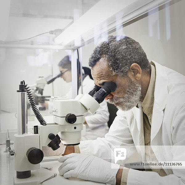 Afroamerikanischer Wissenschaftler mit Mikroskop im Labor