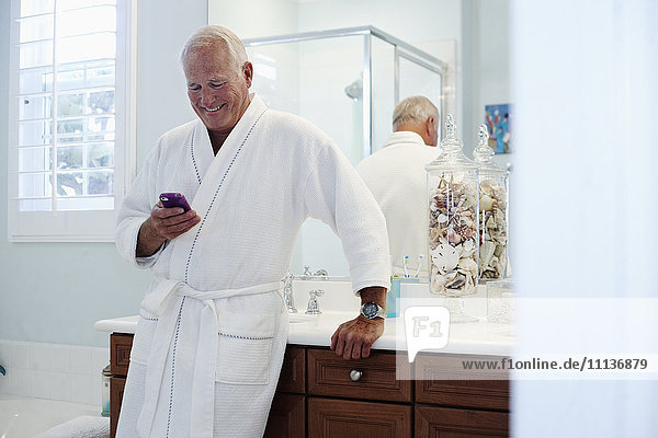 Caucasian man in robe using cell phone