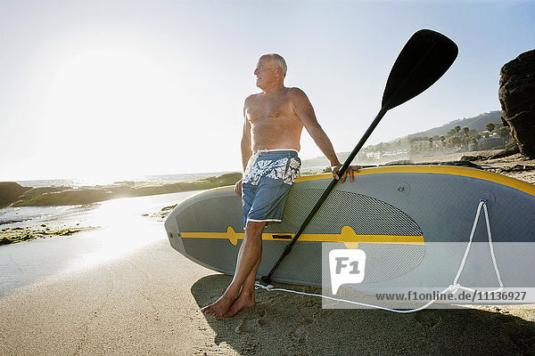 Caucasian man leaning on paddleboard