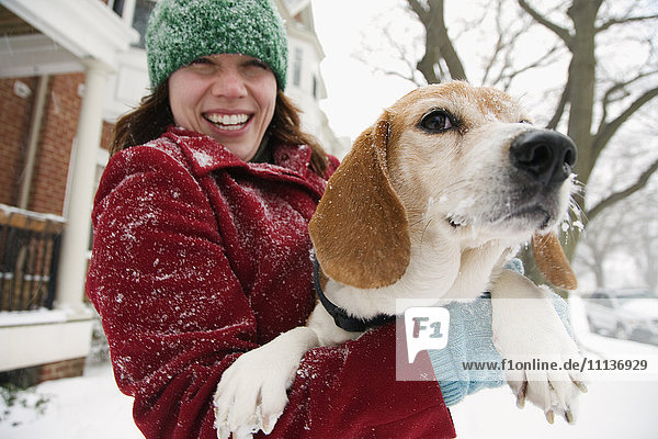 Kaukasische Frau hält Hund im Schnee