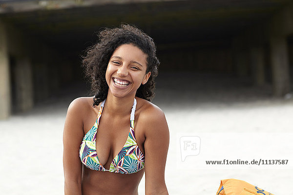 Lachende gemischtrassige Frau am Strand