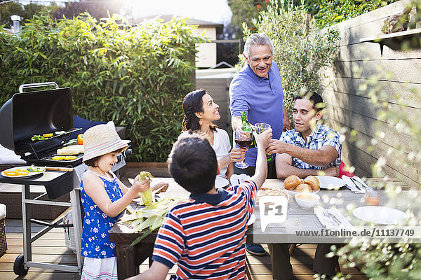 Familie stößt an einem Tisch im Freien aufeinander an