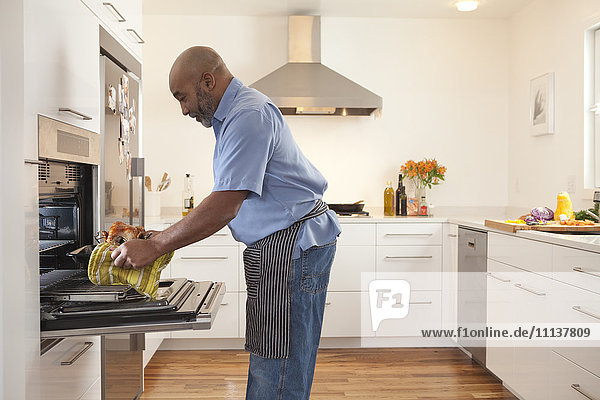 Afroamerikanischer Mann nimmt Essen aus dem Ofen