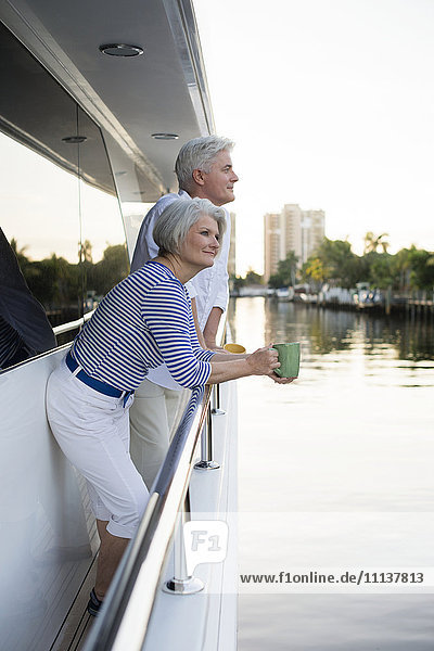 Older Caucasian couple having coffee on boat deck