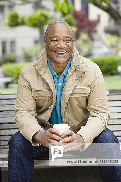 Gemischtrassiger Mann trinkt Kaffee im Park