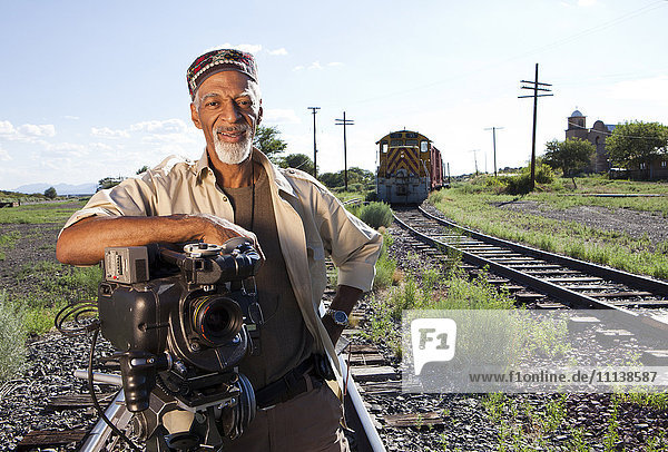 African American man with film camera near railroad tracks