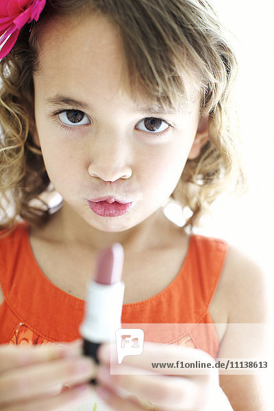 Gemischtrassiges Mädchen spielt mit Lippenstift