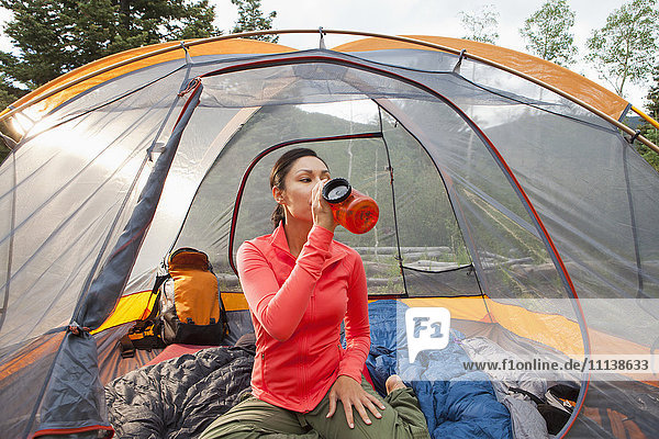 Mixed race woman drinking in tent