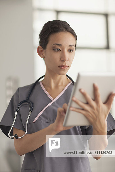 Gemischtrassige Krankenschwester benutzt digitales Tablet