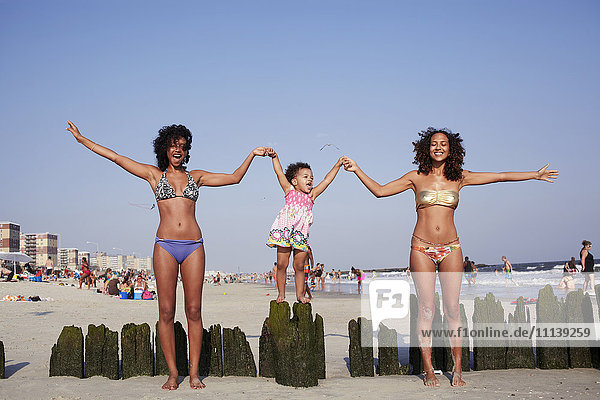 Gemischte Rasse Frauen und Mädchen halten Hände am Strand