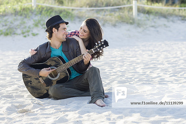 Hispanic couple relaxing on beach