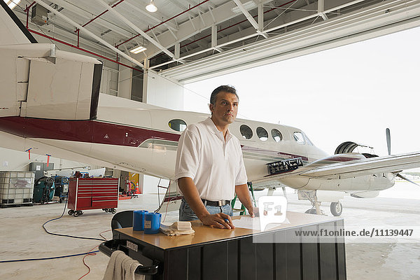 Hispanischer Mann arbeitet in einem Flugzeughangar
