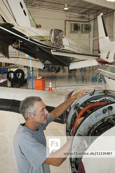Kaukasischer Mann arbeitet in einem Flugzeughangar