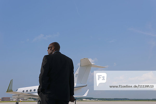 Afroamerikanischer Geschäftsmann auf dem Rollfeld eines Flughafens