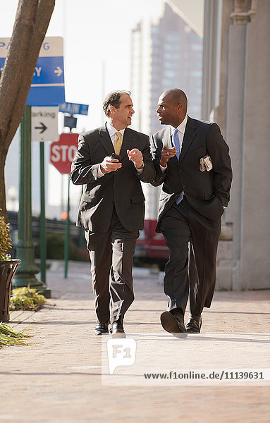 Businessmen walking together on city sidewalk