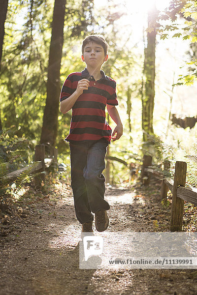 Caucasian boy running on path in forest
